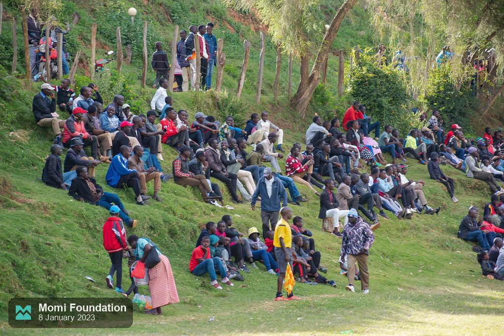 Fans sitting on the grassy hillside overlooking the pitch