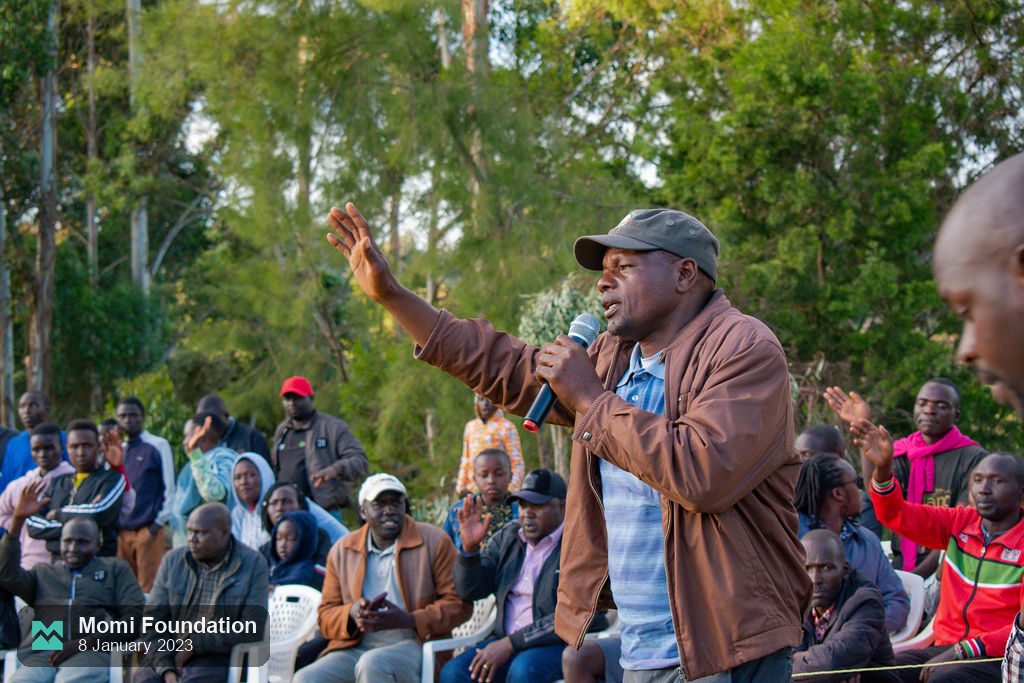 A community elder speaking to the crowd with a microphone