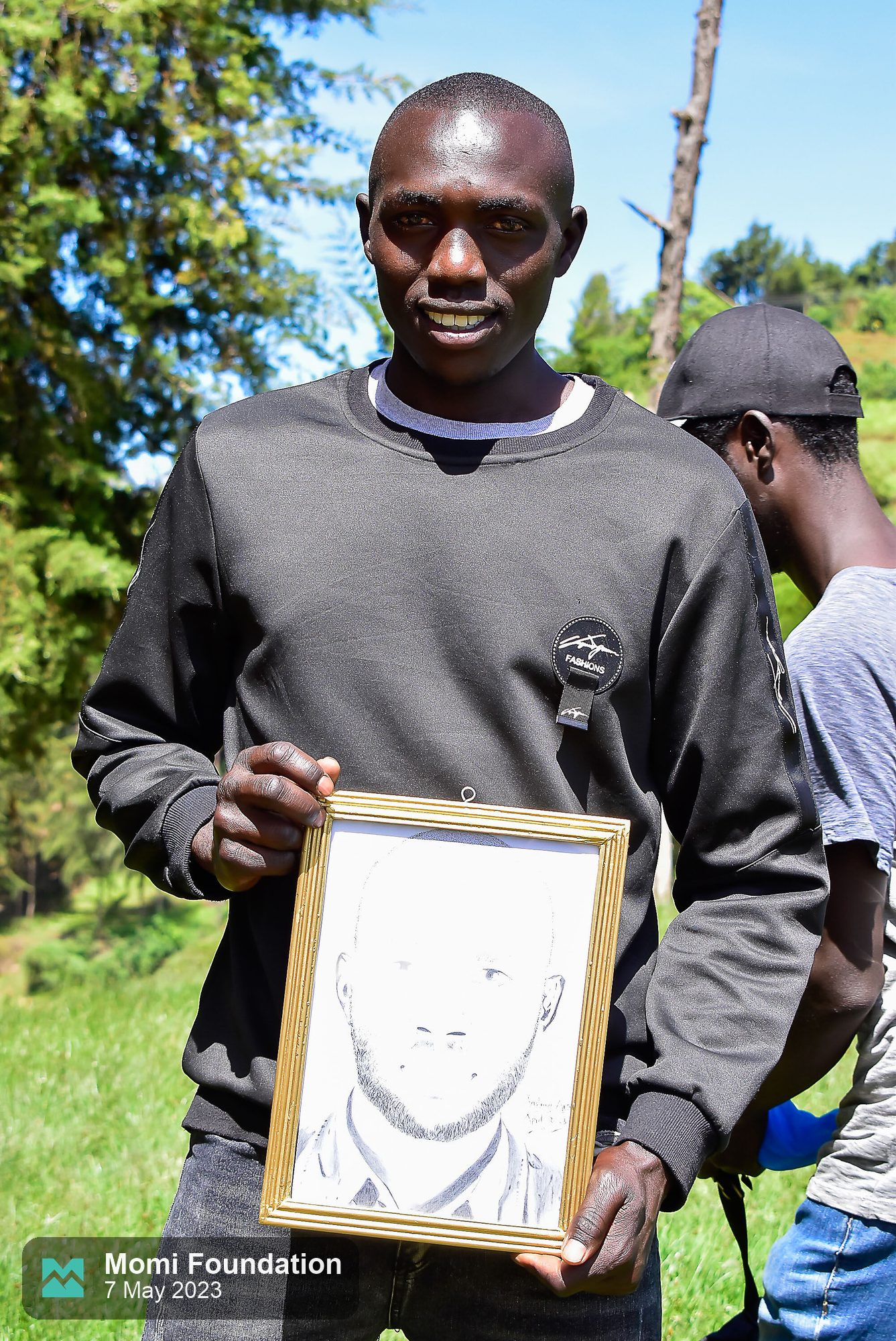 Anselimo holding his framed pencil portrait on match day