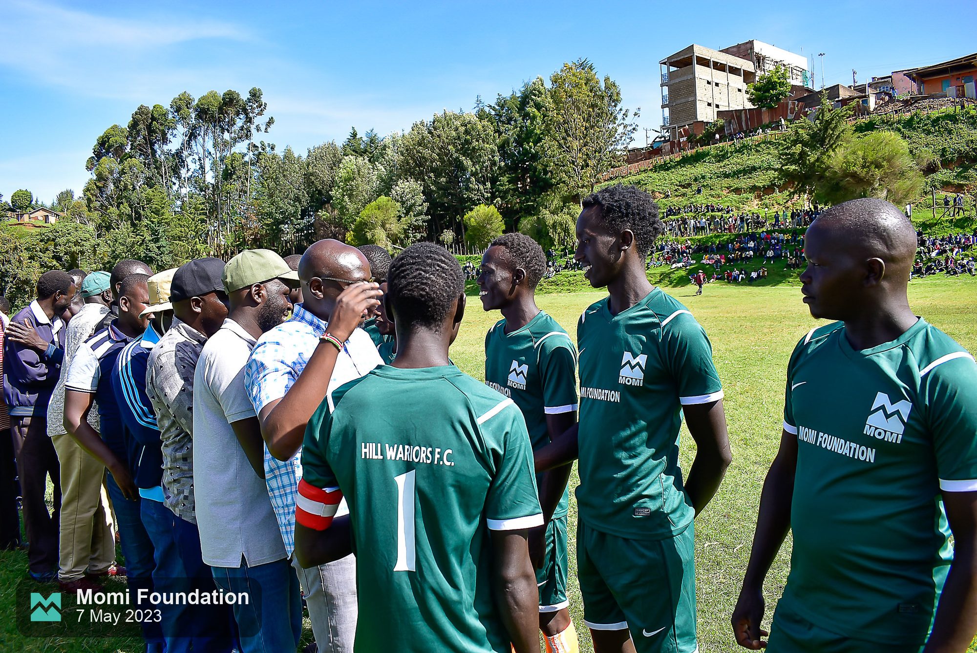 Hill Warriors F.C. players in Momi Foundation kits greeting guests before a match