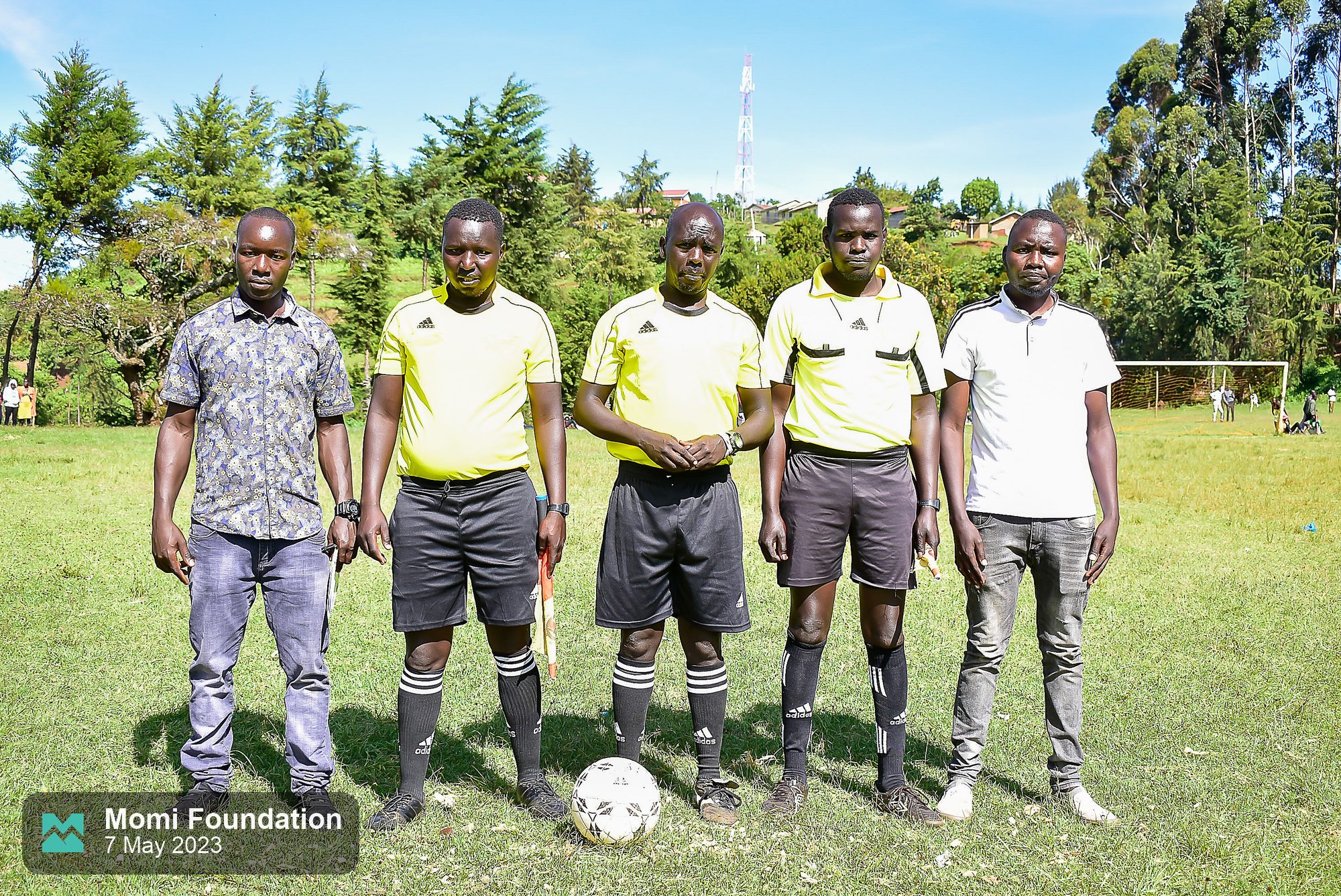 The match officials standing together with the match ball