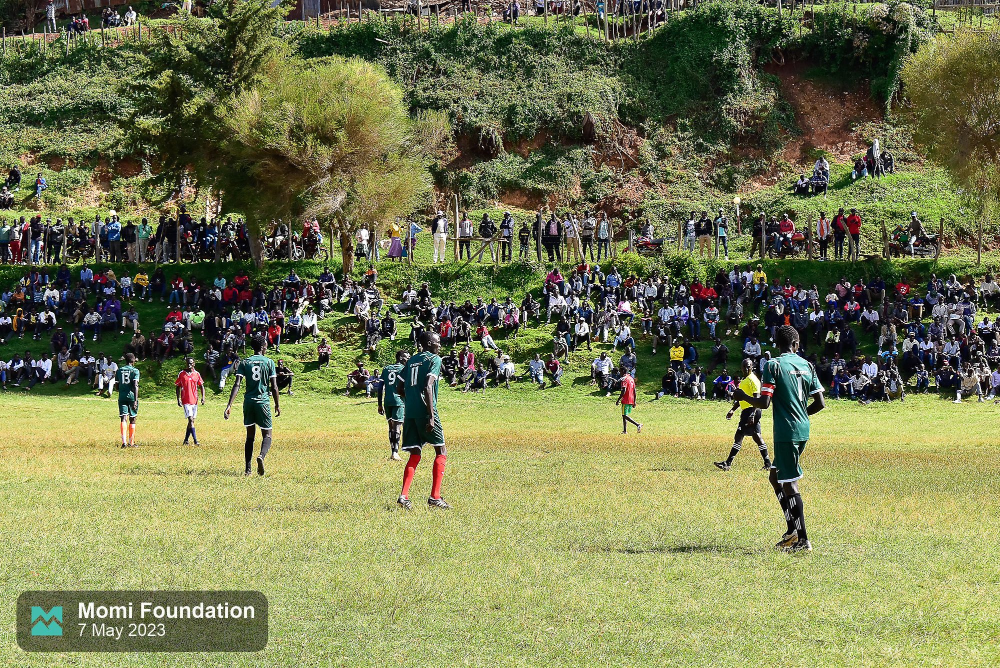 Fans sitting across the hillside overlooking the pitch
