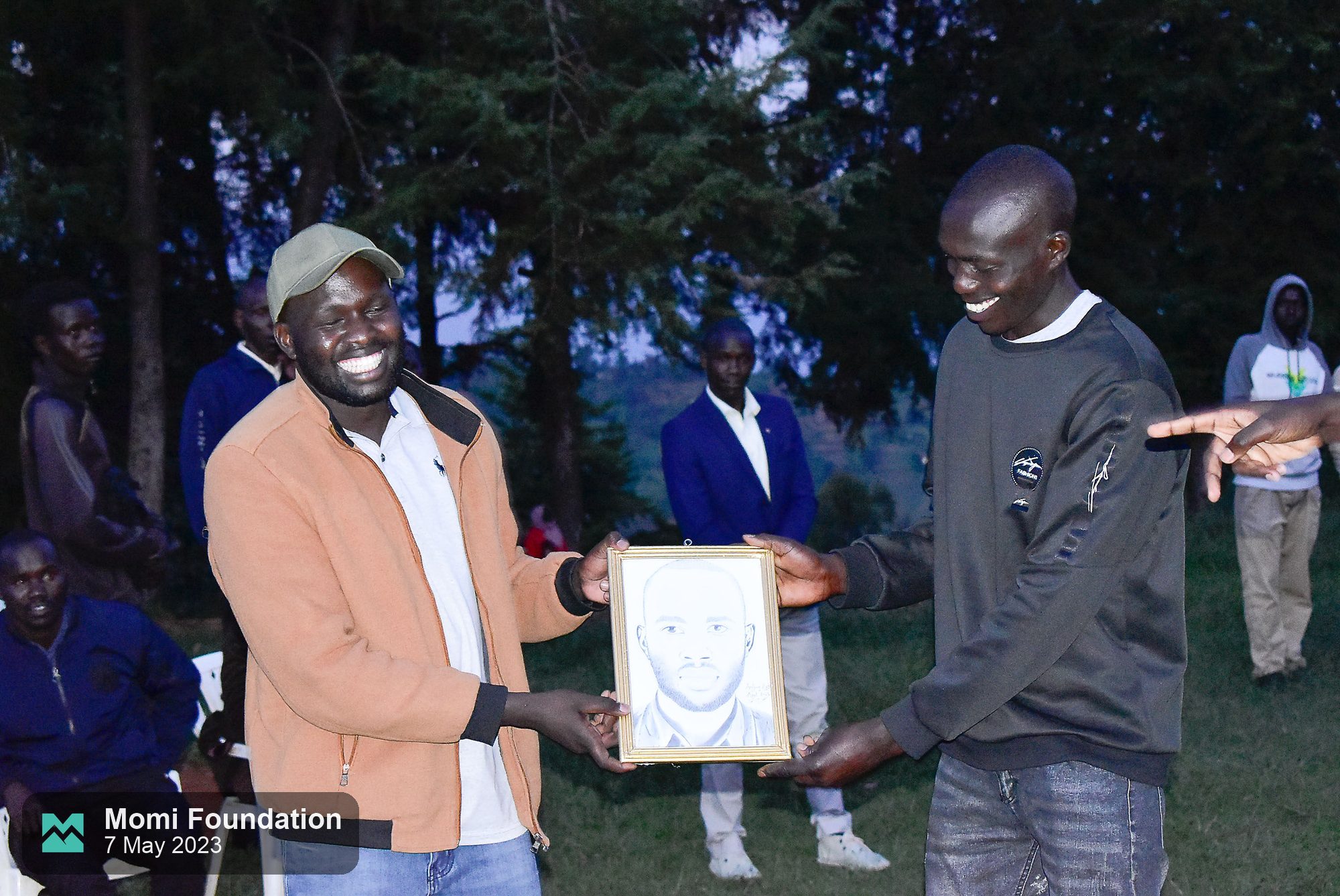 A framed pencil portrait being handed over at the evening ceremony