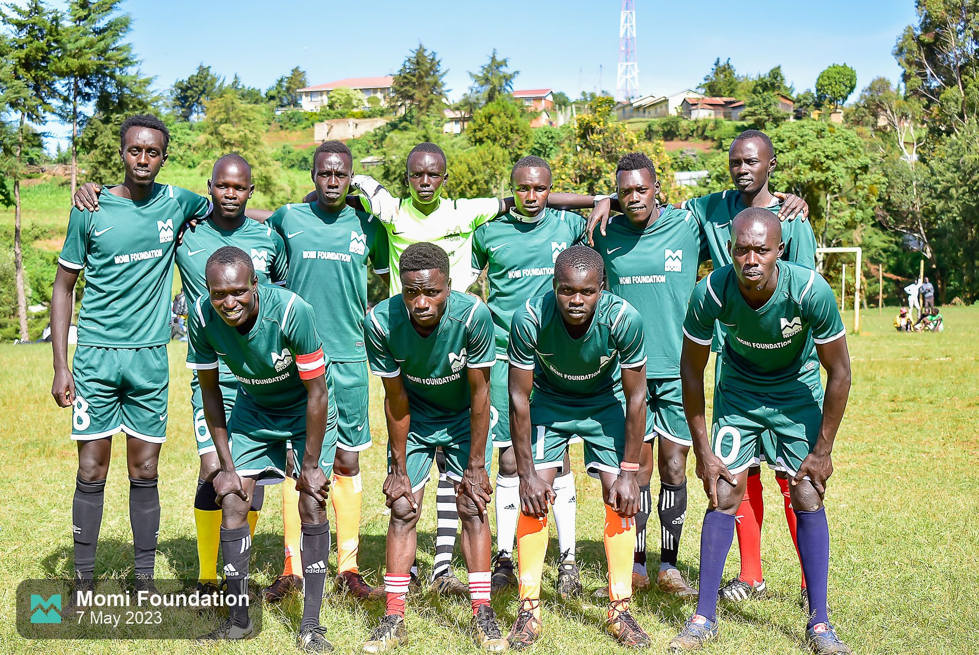 Players in green Momi Foundation kits posing for a team photo