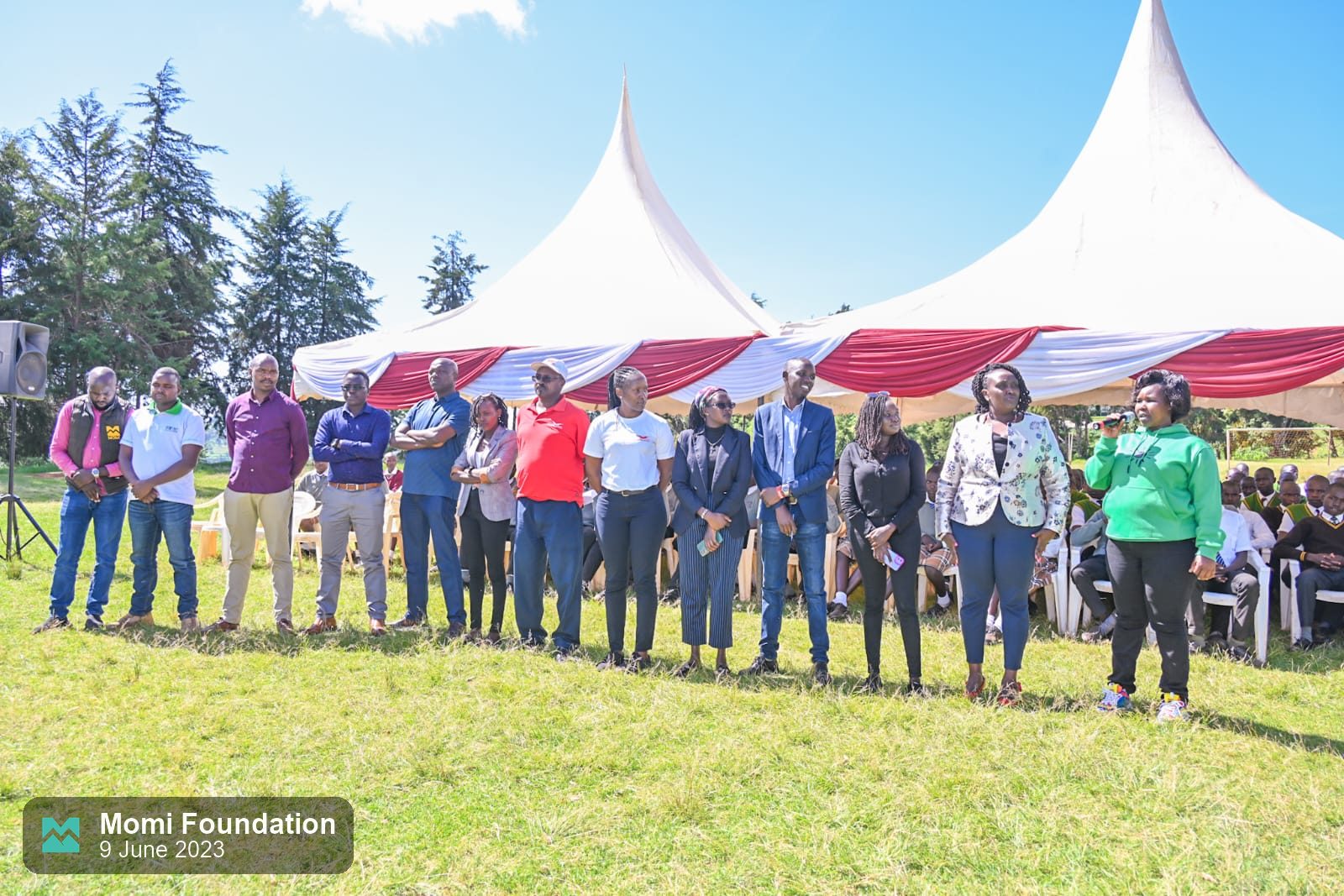 Guests and organisers standing in a line in front of the tents