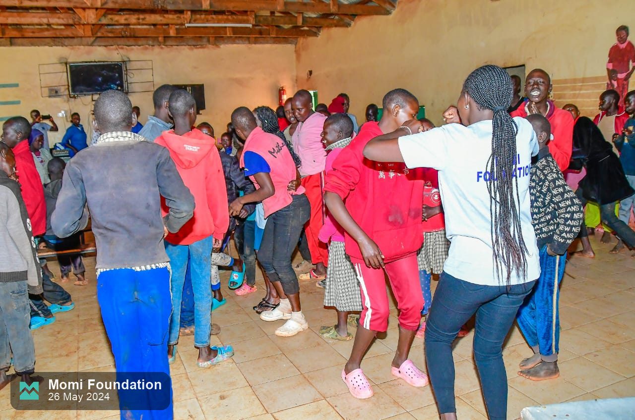 Pupils and volunteers dancing together in the school hall