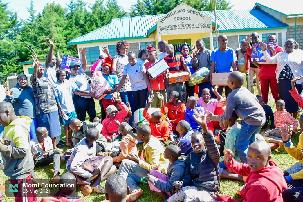 Pupils, teachers and the Momi Foundation team celebrating outside the school with donated items