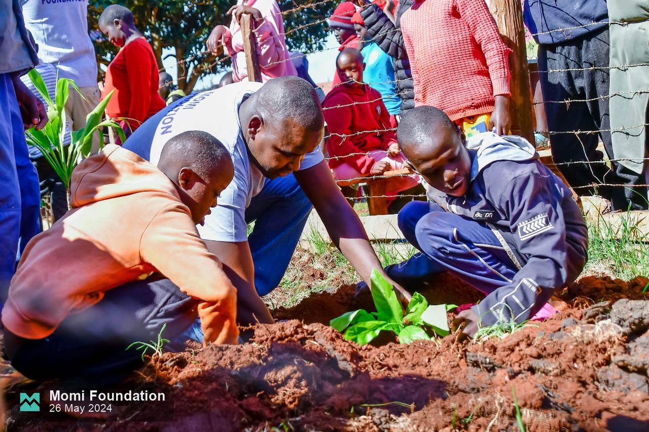 A Momi Foundation volunteer and pupils planting a seedling together
