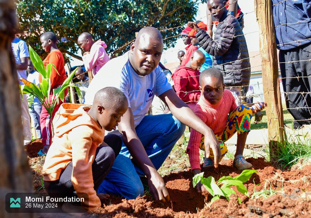 A volunteer shows pupils how to plant a seedling