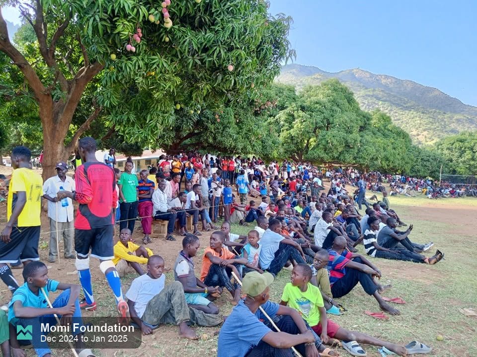 Fans seated under mango trees beside the pitch at the Arror ward tournament